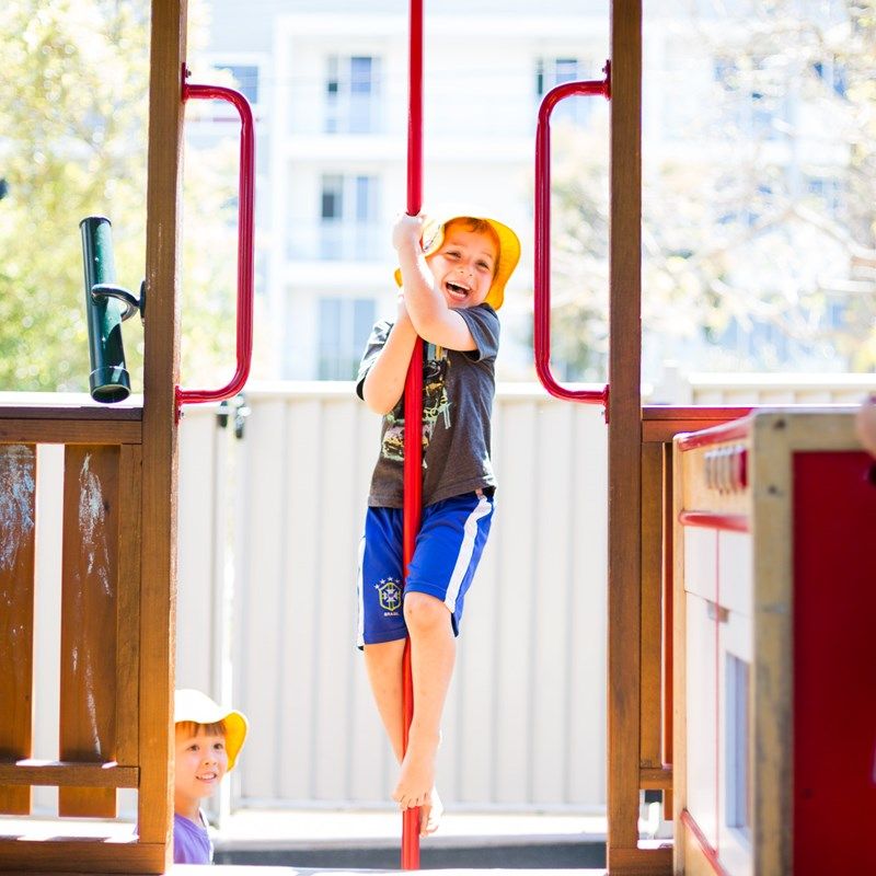 A child climbing the fireman’s pole in the playground