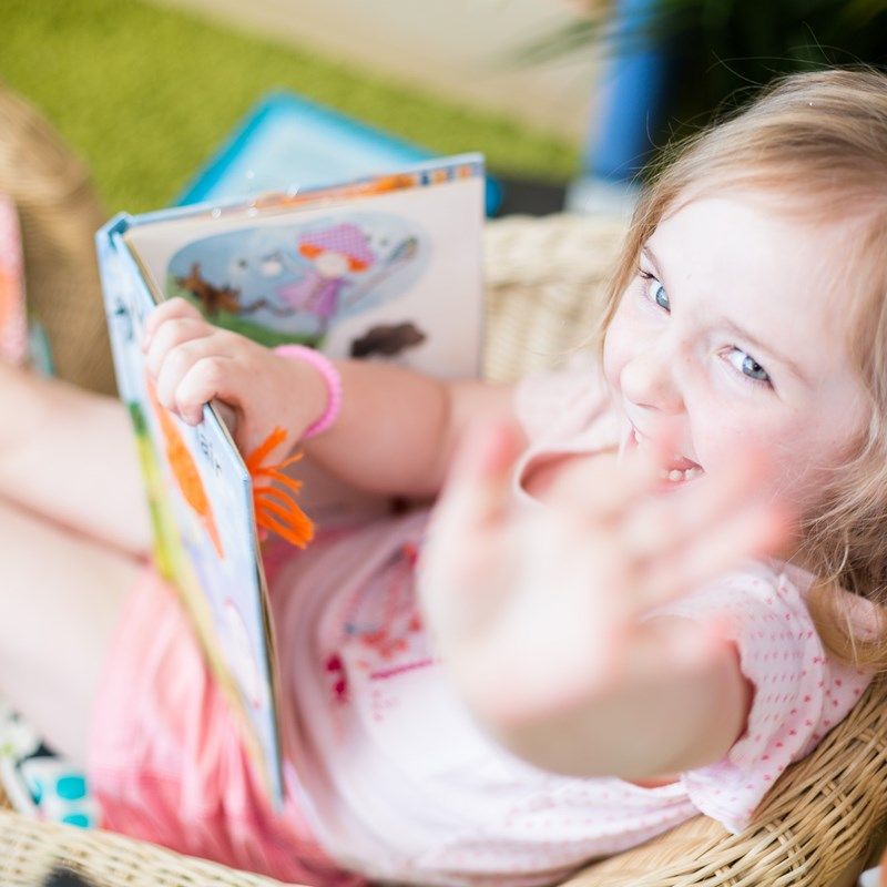 A smiling girl holding up her favourite picture book