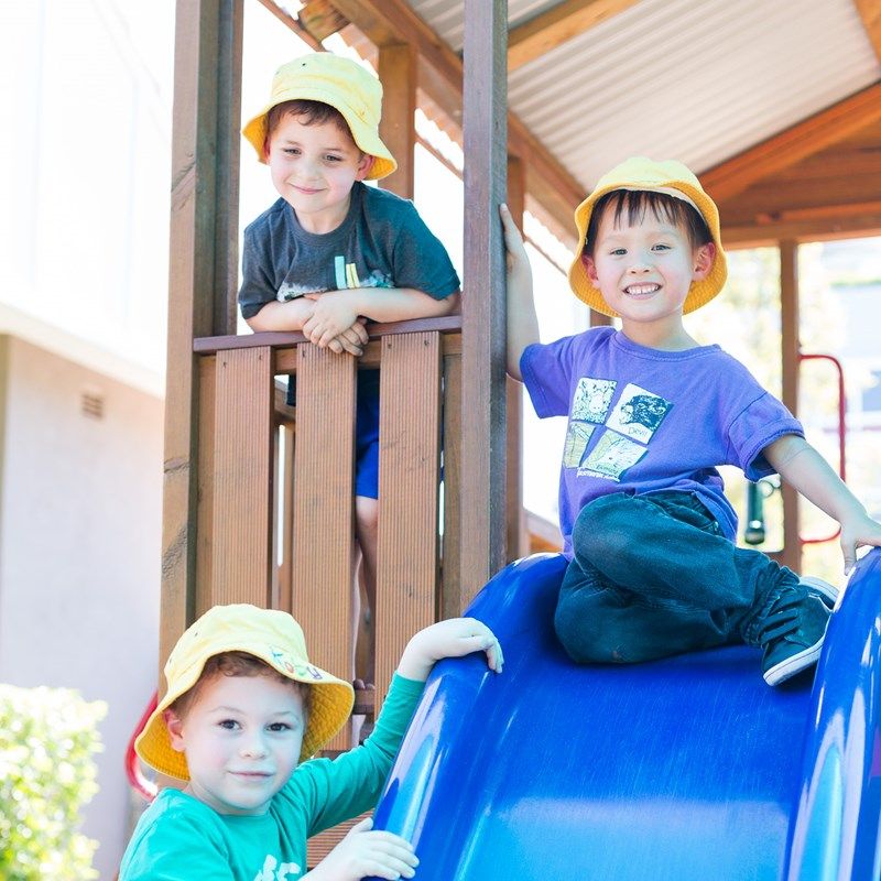 Friends in sun hats playing together on the slide