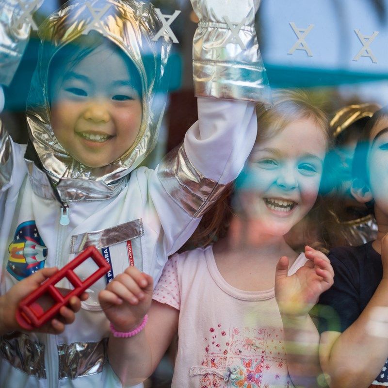Preschoolers dressed up as astronauts, grinning during a space project