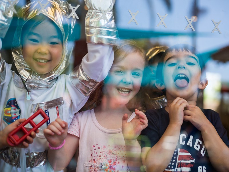 Kids in dress-up playing and smiling through window