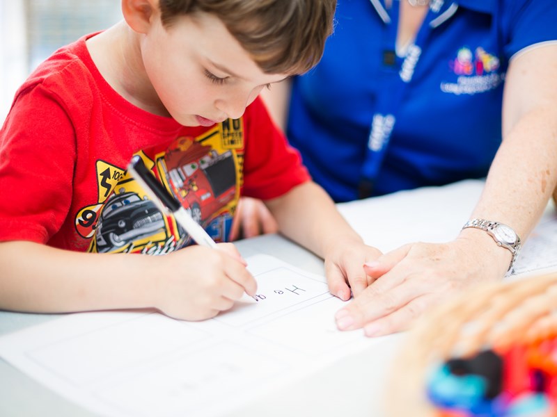 Young boy drawing with educator